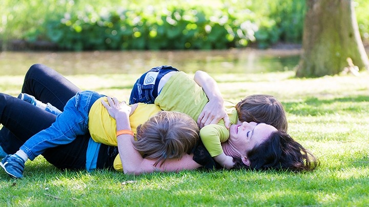 Woman cuddling her two children in the park