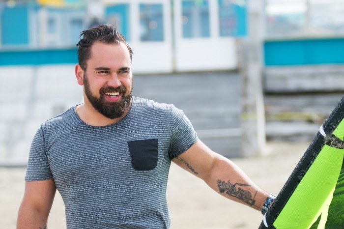 Smiling man with hand tattoo close up with Kitesurfing