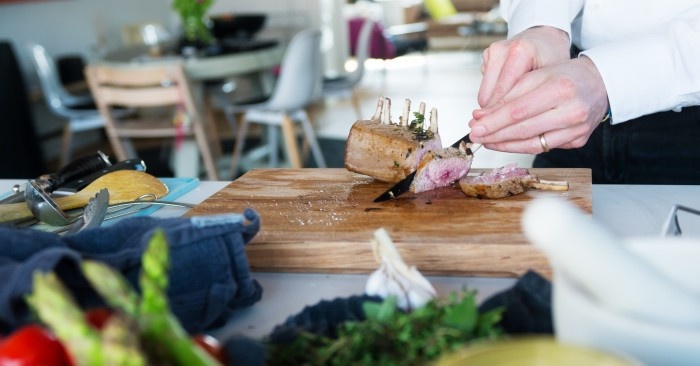 Man cutting roasted meat in a wooden cutting board