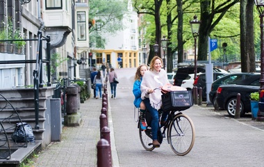 Woman biking with her daughter in her back