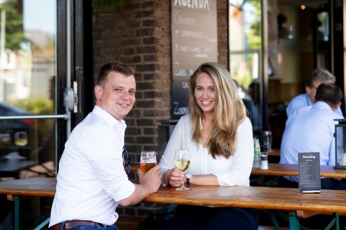 woman and man smiling at the camera while holding drinks