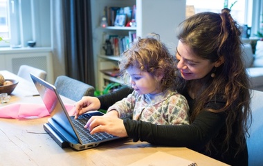 Woman working on her laptop with her daughter in her lap