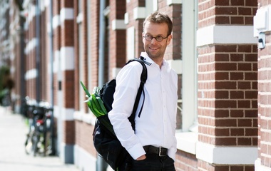 Man with glasses posing infront of a building