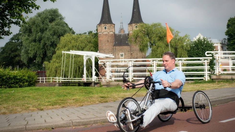 Man cycling a bike with his hands with a castle in the background