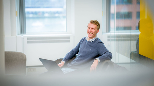 Medewerker zit op een bank met laptop