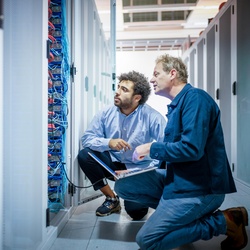 Twee medewerkers kijken samen naar een computerkast