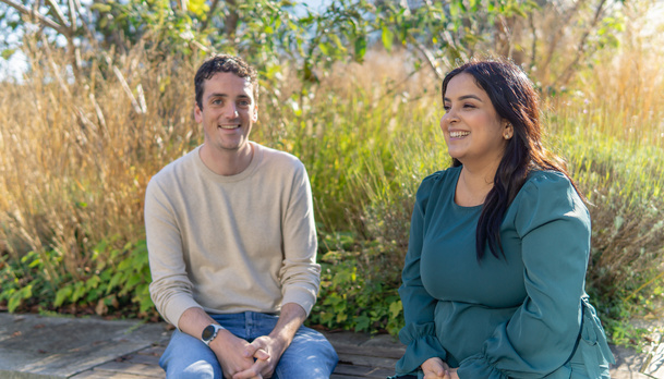 Twee medewerkers zitten buiten op een bankje