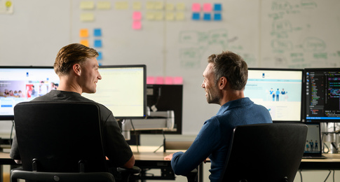 Twee medewerkers zitten achter een bureau aan het werk op de computer