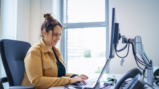 Medewerker zit te werken op de computer aan een bureau