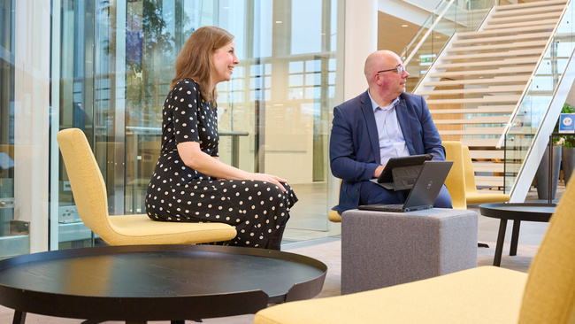 Twee medewerkers zitten met hun laptop in de hal