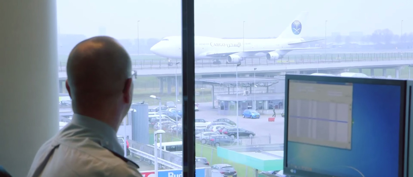 Een risico analyst kijkt uit het raam en houdt toezicht op een luchthaven.