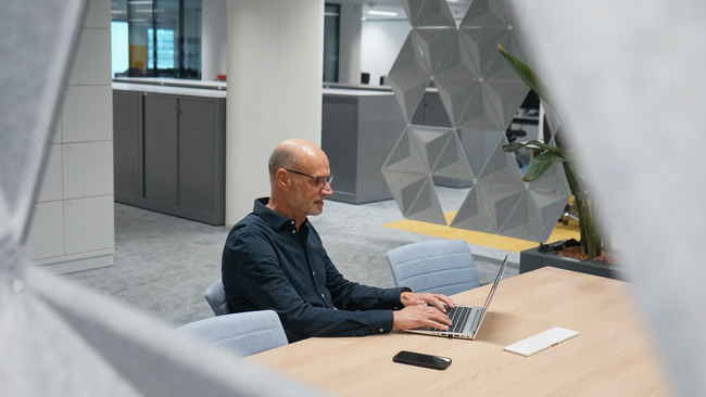 Medewerker zit aan tafel met laptop