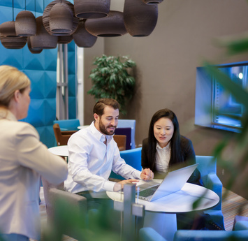 Twee collega's zijn met elkaar in gesprek en kijken naar een laptop