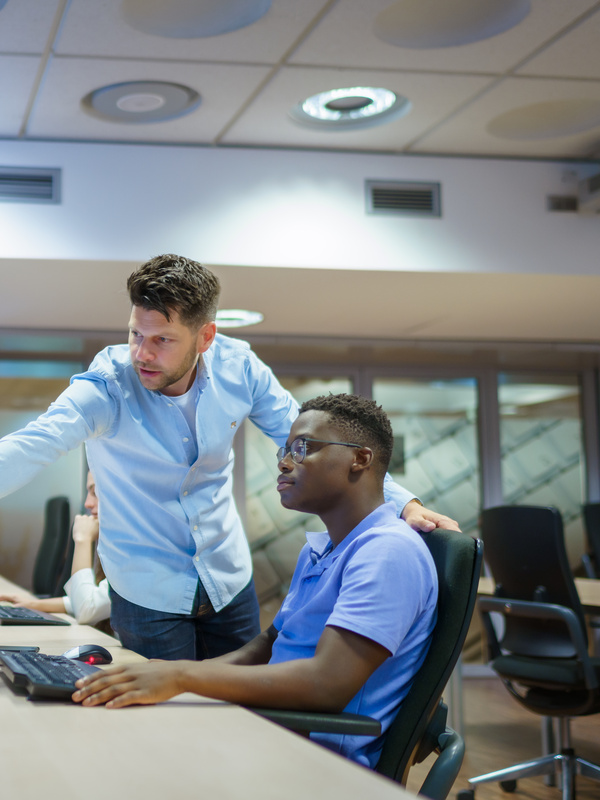 Een medewerker legt een collega iets uit via de computer