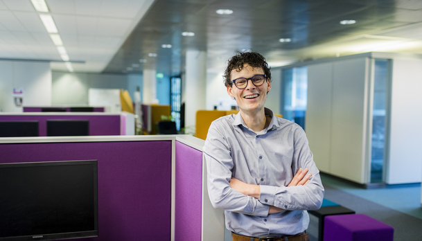 Man leunt ergens tegenaan en is aan het lachen