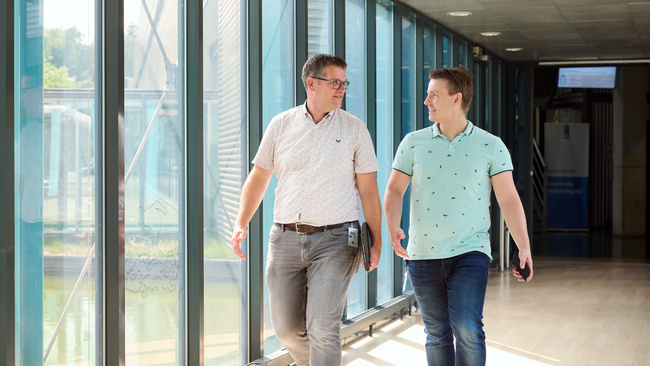 Twee werknemers lopen door de hal