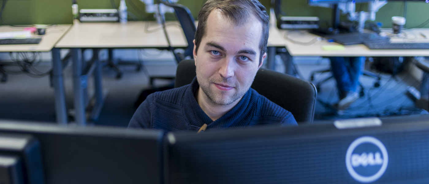 man achter laptop kijkt in de camera