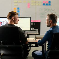 Twee medewerkers zitten achter een bureau aan het werk op de computer