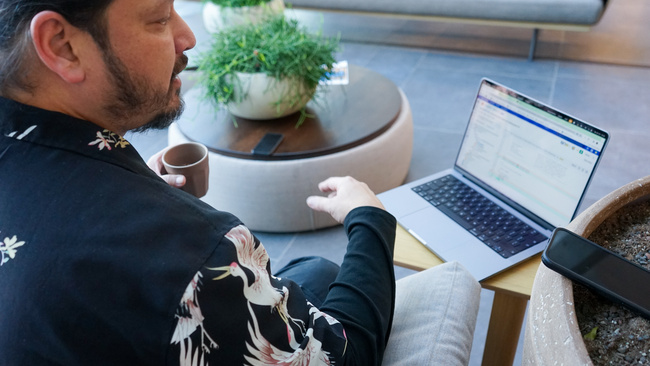 Medewerker zit op een bank met zijn laptop