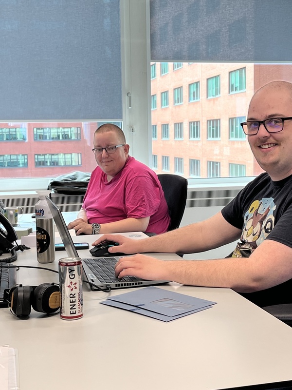 Twee medewerkers zitten aan een bureau