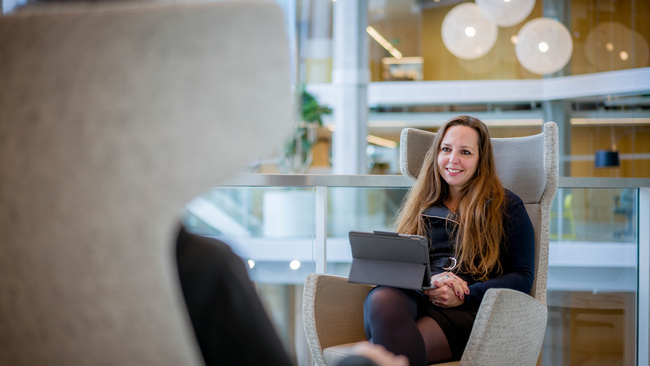 Medewerker zit met haar tablet op een stoel