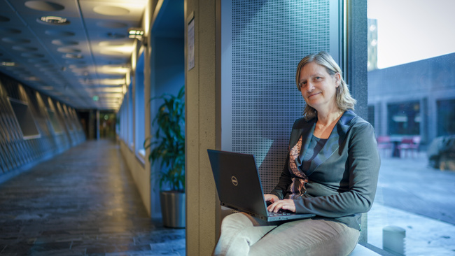 Marijke, adviseur AO/IC, zit op een bankje met haar laptop