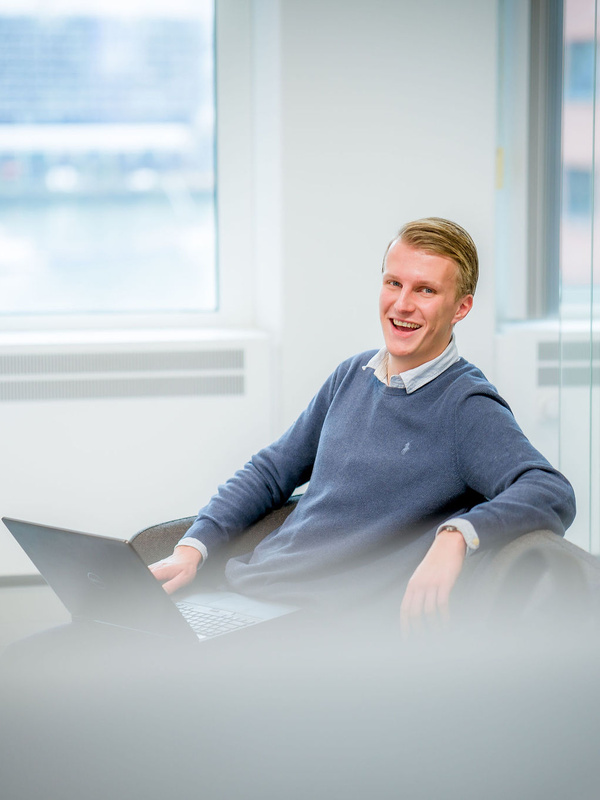 Medewerker zit op een bank met laptop