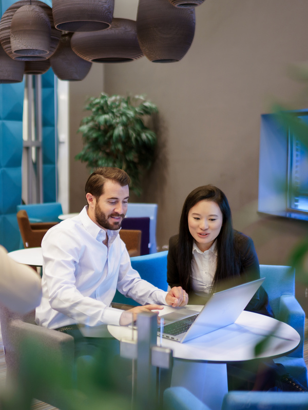 Twee collega's zijn met elkaar in gesprek en kijken naar een laptop