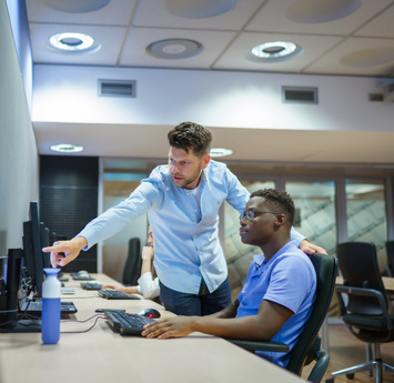 Een medewerker legt een collega iets uit via de computer