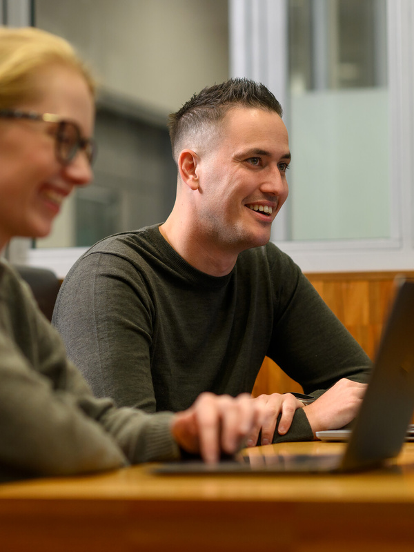 Twee medewerkers zitten achter hun laptop