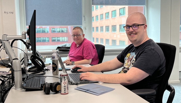 Twee medewerkers zitten aan een bureau