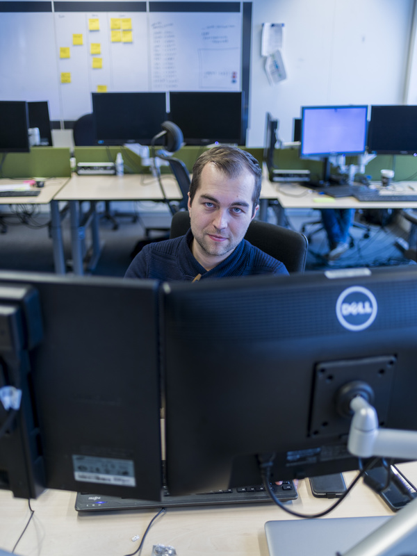 man achter laptop kijkt in de camera