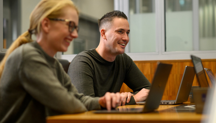 Twee medewerkers zitten achter hun laptop
