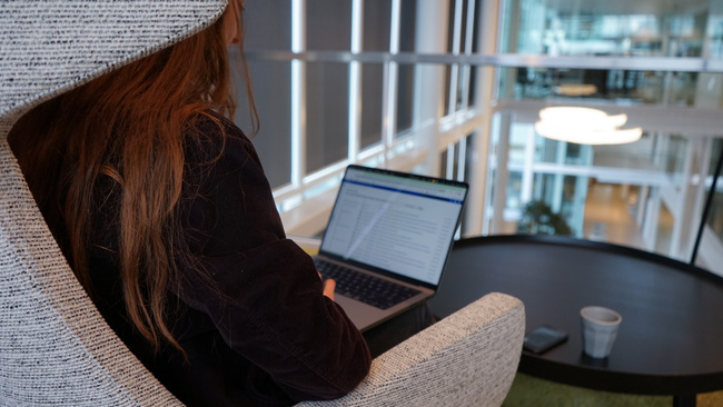 Medewerker zit op een stoel achter haar laptop