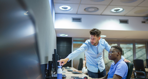 Een medewerker legt een collega iets uit via de computer