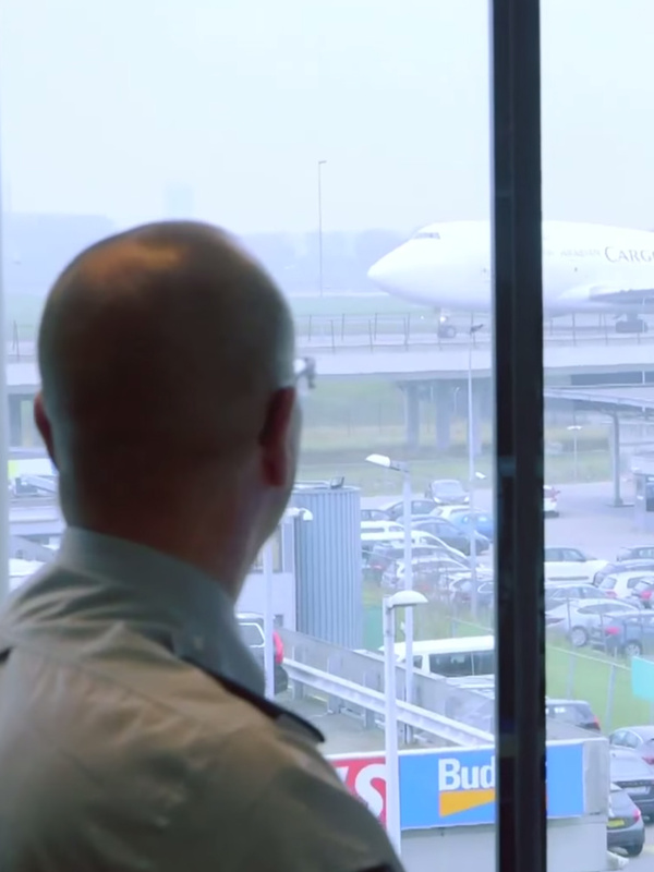 Een risico analyst kijkt uit het raam en houdt toezicht op een luchthaven.
