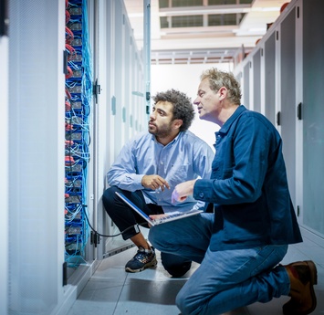 Twee medewerkers kijken samen naar een computerkast