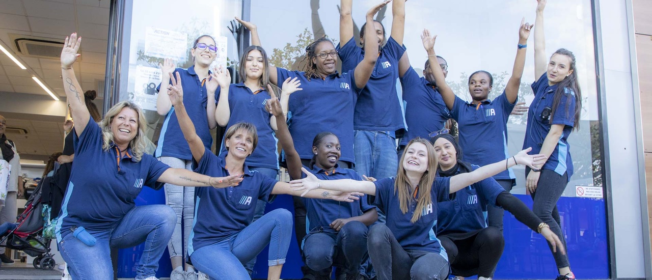 Un groupe d’employés d’Action enthousiastes devant un magasin Action