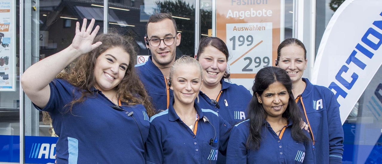 Gruppe begeisterter Mitarbeiter von Action vor einer Action Filiale