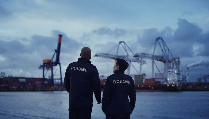 Twee medewerkers in uniform staan in de haven