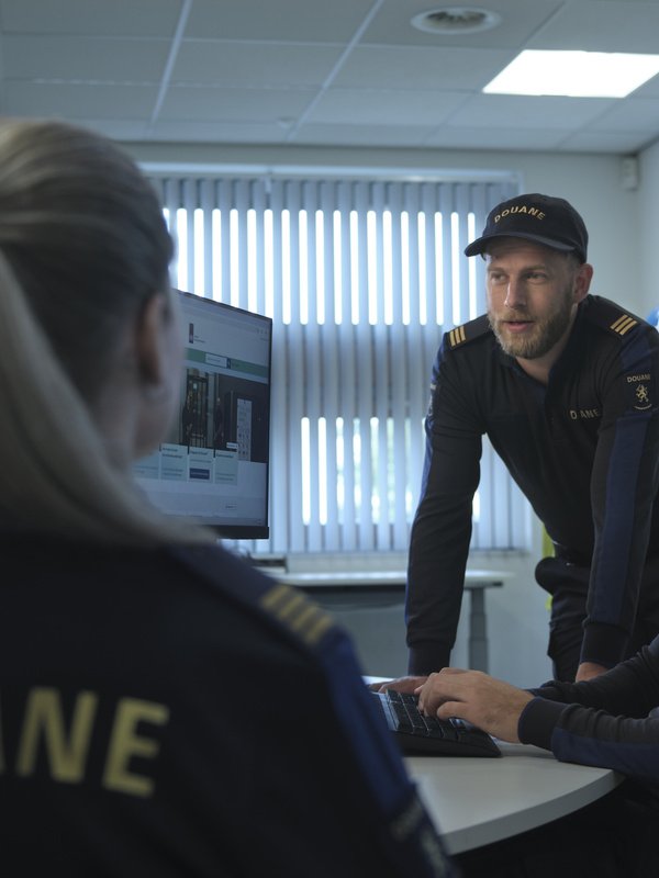 Douane medewerkers in overleg aan het werk.